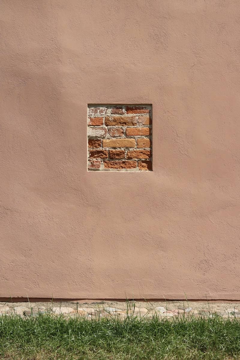 A red fire hydrant sitting next to a pink wall