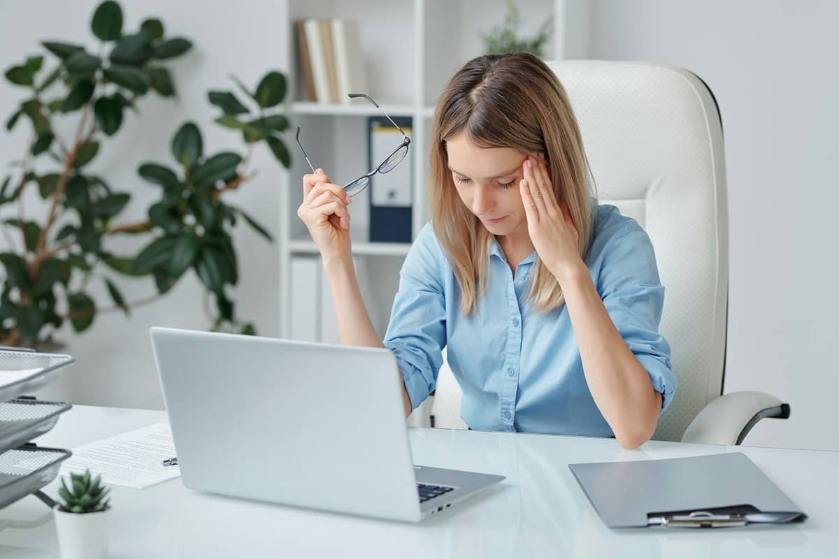 Tired businesswoman touching temple sitting at a desk