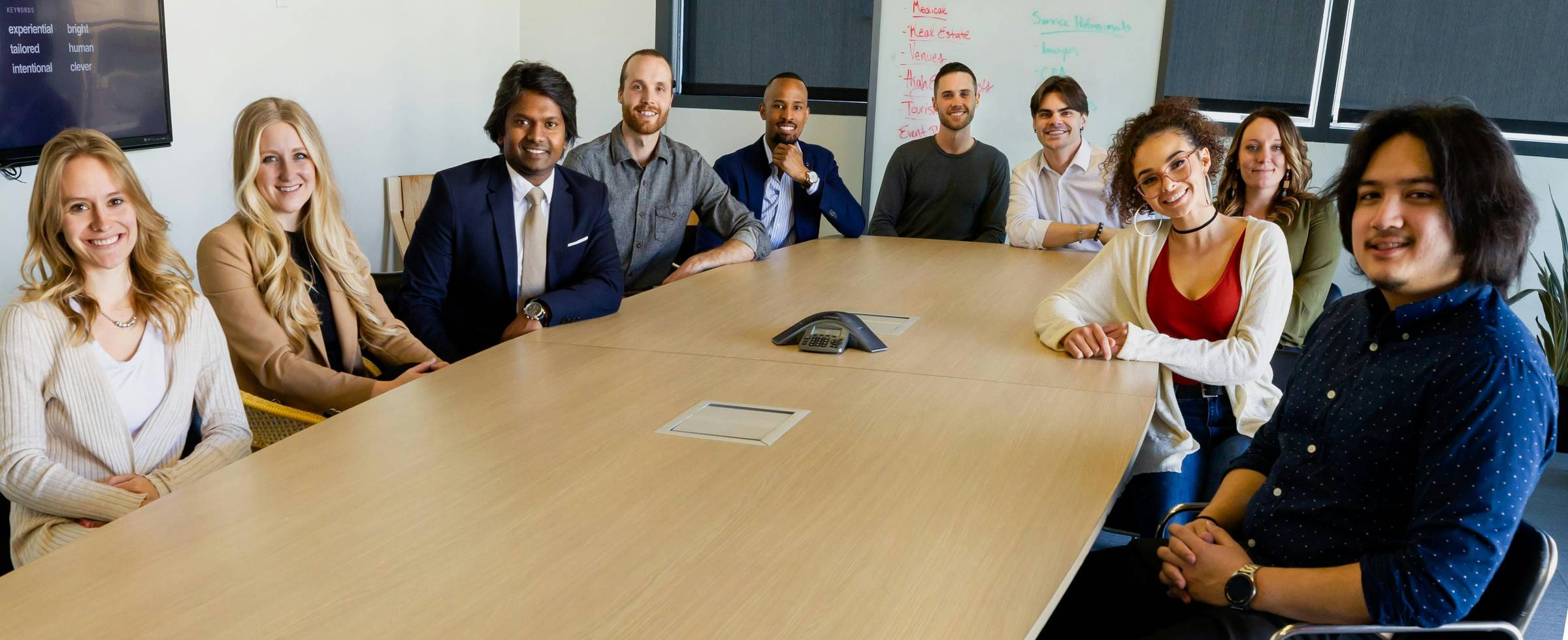 Group of people sitting in chairs in front of a brown wooden table