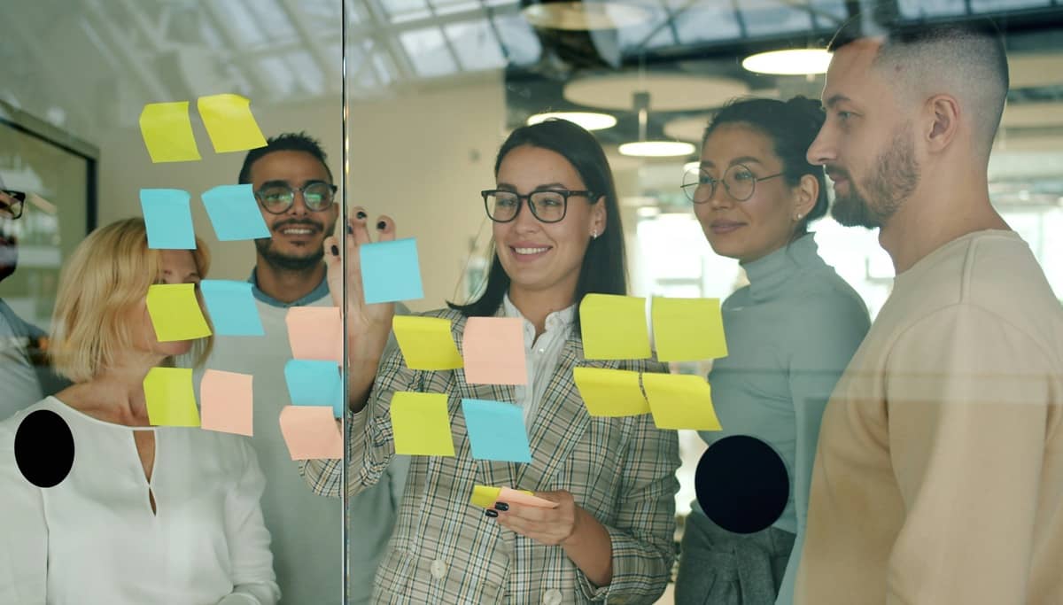 Team collaborating with sticky notes on a glass wall