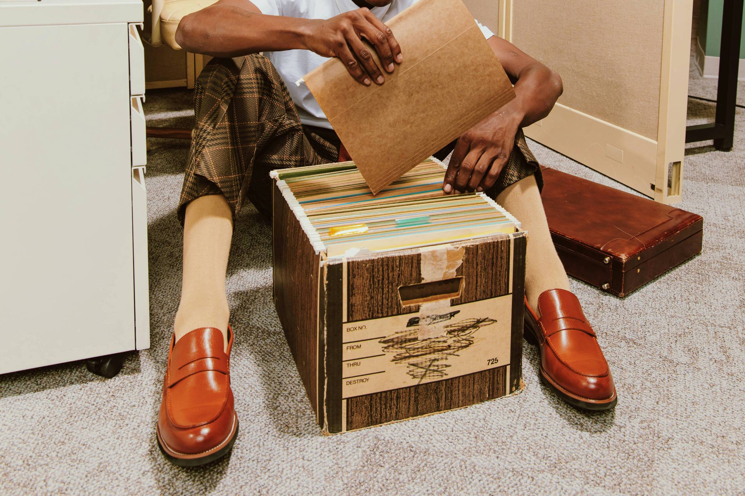 A man sitting on the floor with a file box.
