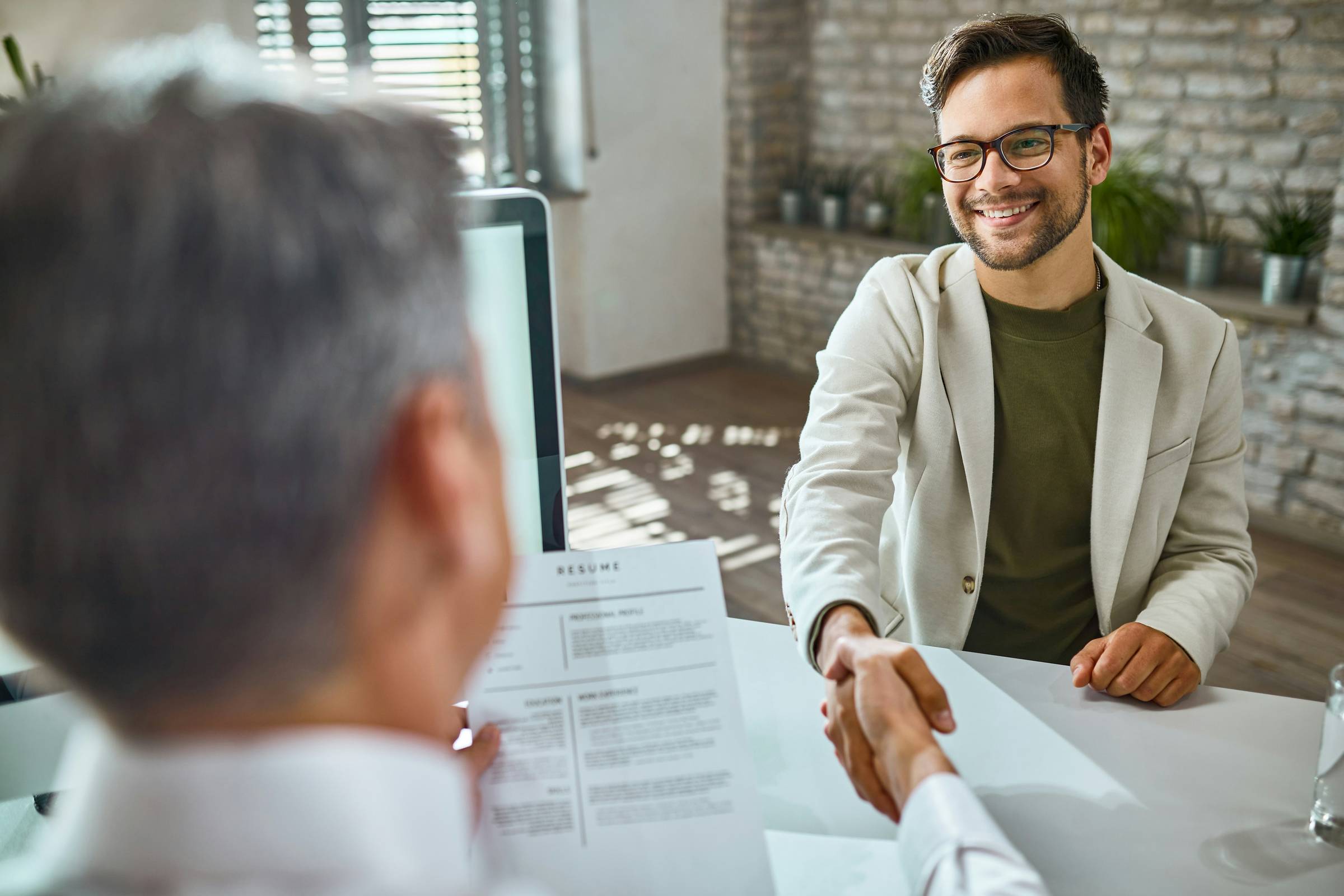 Happy male candidate greeting a member of the HR team on a job interview in the office.