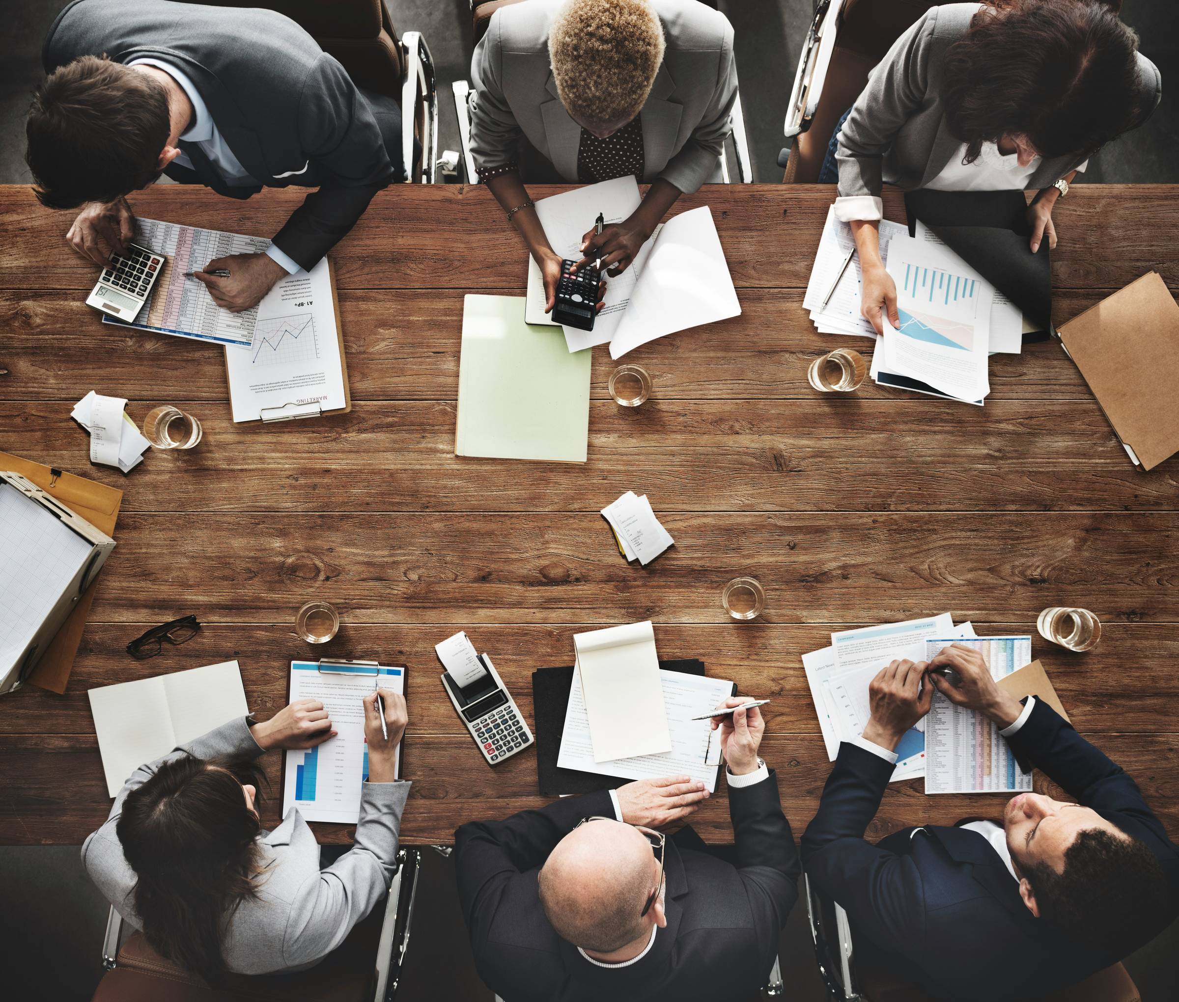 Business people in a group meeting shot from top view around a conference room table.