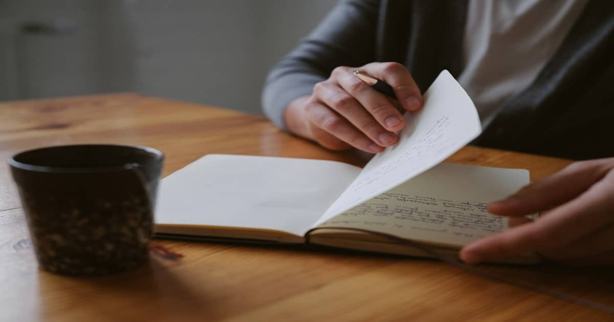 A person sitting at a table writing in a notebook.