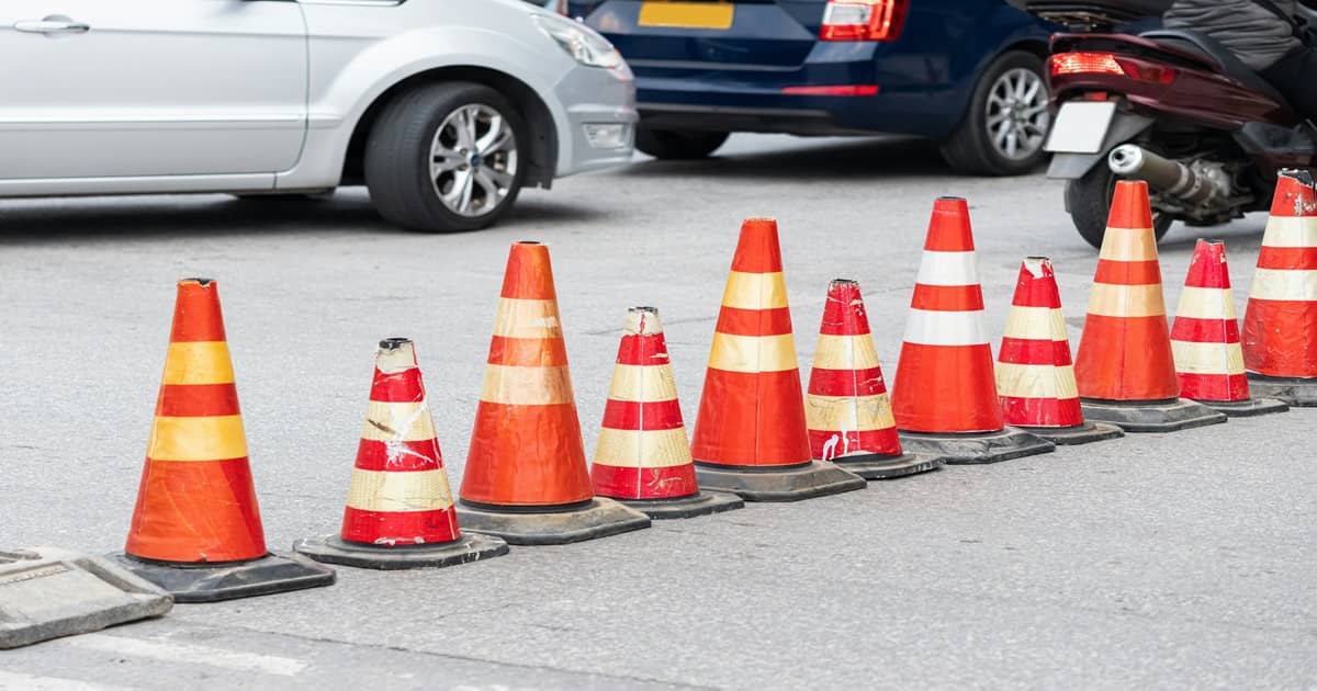 A row of red and white safety cones on a street.