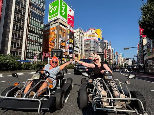 two people high five on the streets of japan while riding in go karts