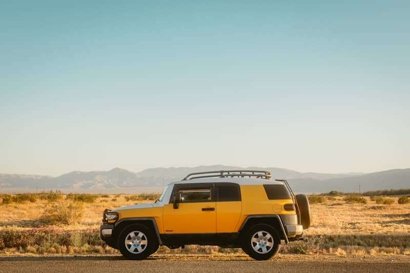 Yellow suv parked on a desert road
