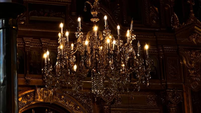 An ornate crystal chandelier glows in a dark room.