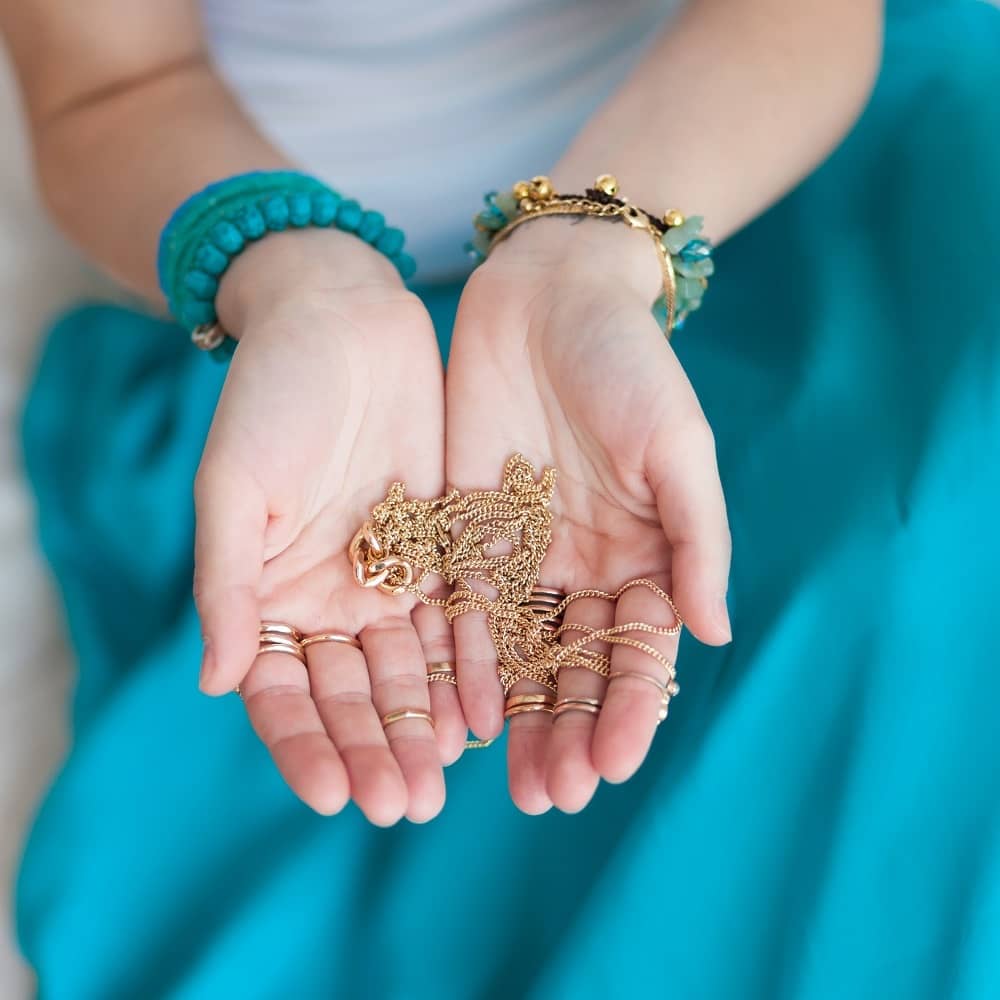 woman holding gold chain necklace