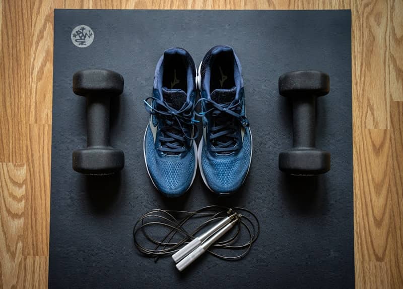 blue and black athletic shoes next to weights
