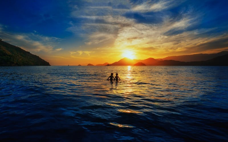 A couple of people standing on top of a body of water