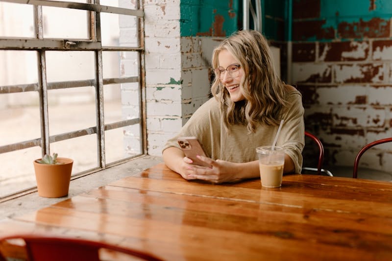 a woman sitting at a table looking at her cell phone