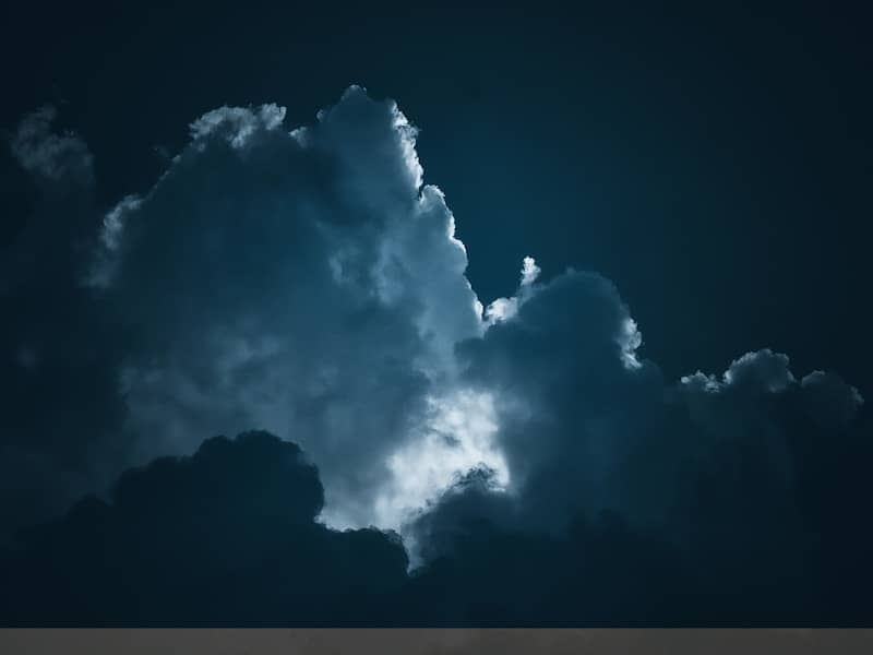 Dramatic clouds are illuminated in the night sky.