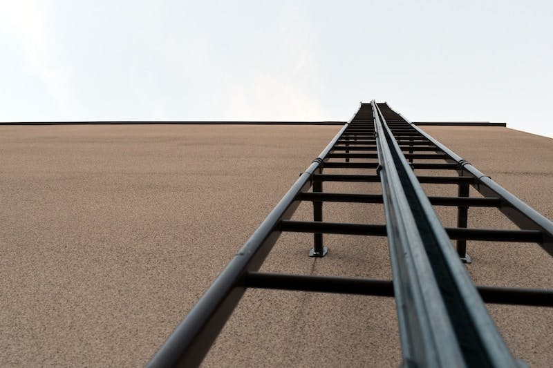 back metal ladder beside beige wall during daytime