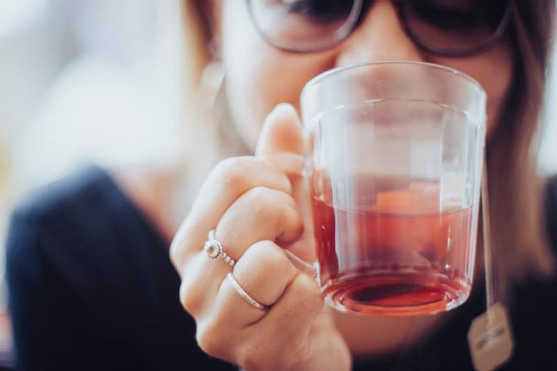 woman holding clear drinking glass with red liquid