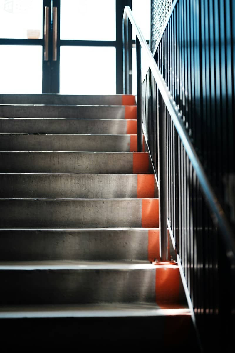 Concrete stairs with bright orange safety strips leading up to a glass doorway