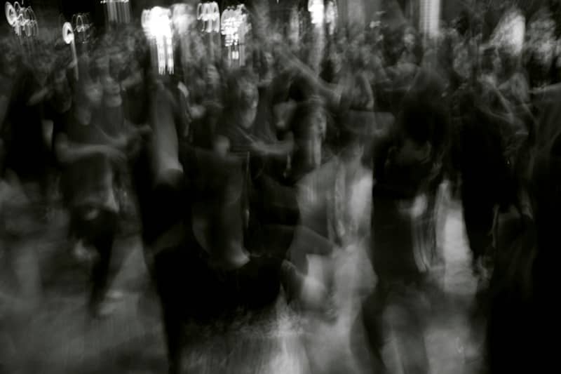 A crowd of people dancing in a long exposure black and white blur