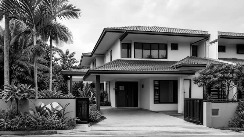 A modern two-story house with a tiled roof and palm trees in black and white