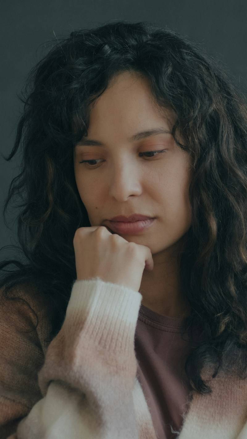 A woman with curly dark hair resting her chin on her hand