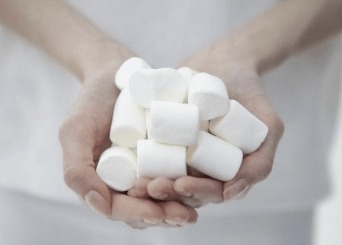 Hand holding many marshmallows