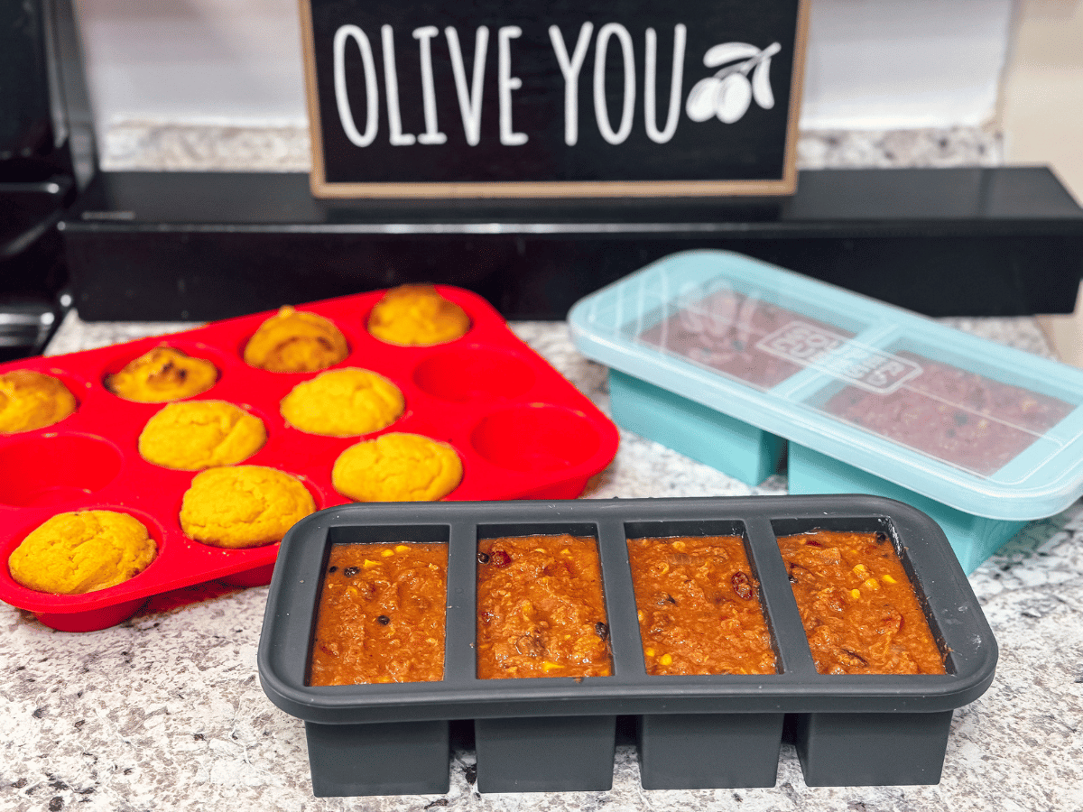 A 4-well 1-cup portion silicone Souper Cubes freezer tray is filled with easy homemade sweet potato chili & sits on a countertop. A second 2-well, 2-cup portion silicone Souper Cubes tray is also filled with chili & closed with a translucent plastic lid. 