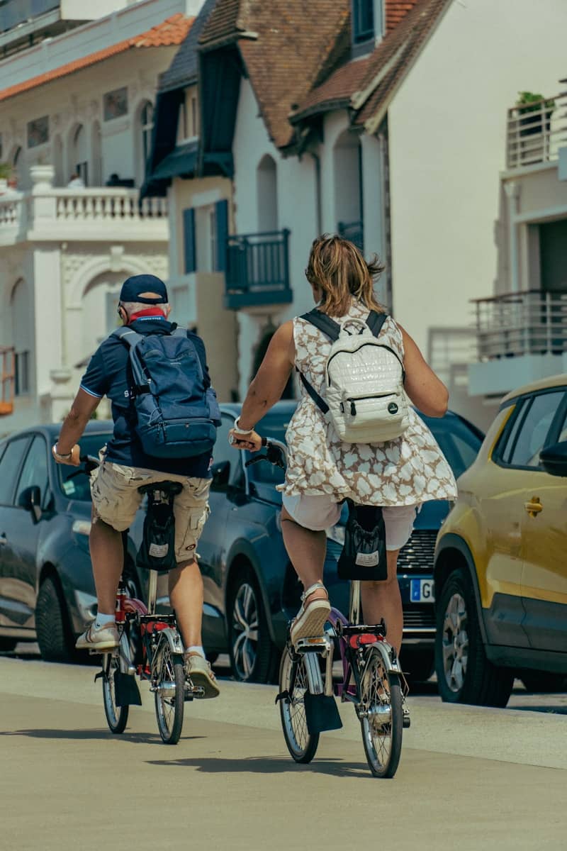 Two people ride folding bikes down a street.