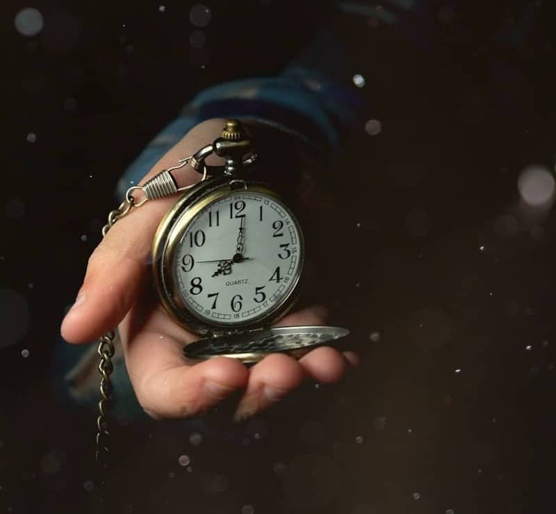 a person holding a clock in their hand