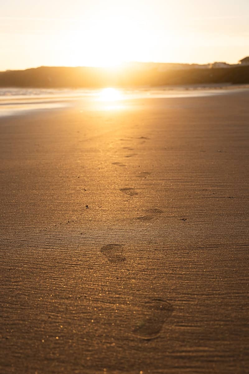 Footprints lead toward the sunset on the beach.