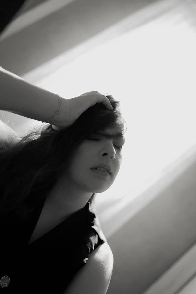 A woman touches her head with closed eyes