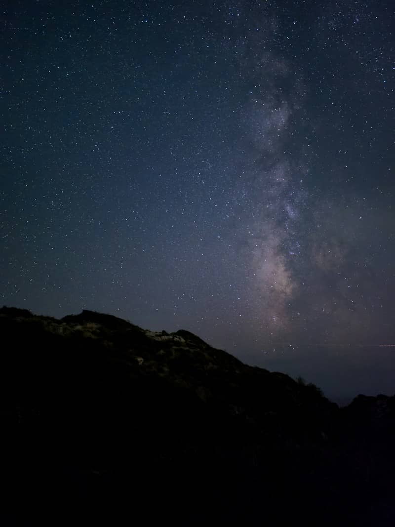 Milky way galaxy shines above dark mountains.