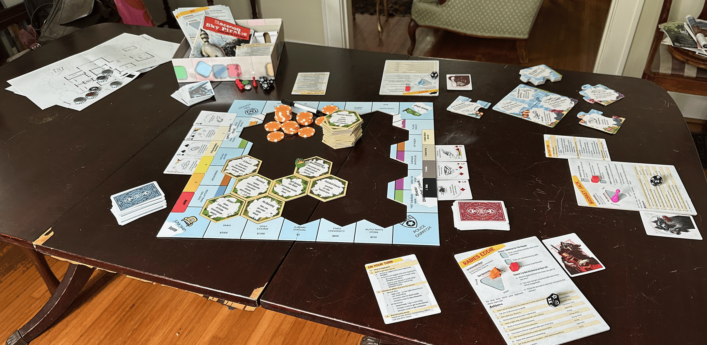 House maps, custom bottle caps, rules reference cards, 30 raccoon portrait cards, 60 disaster cards, frame board, 30 hex tiles, 20 poker chips, dry-erase marker, 6 raccoon dice, 6 double-sided character boards, 15 ship puzzle pieces, a dumpster fire meeple & more