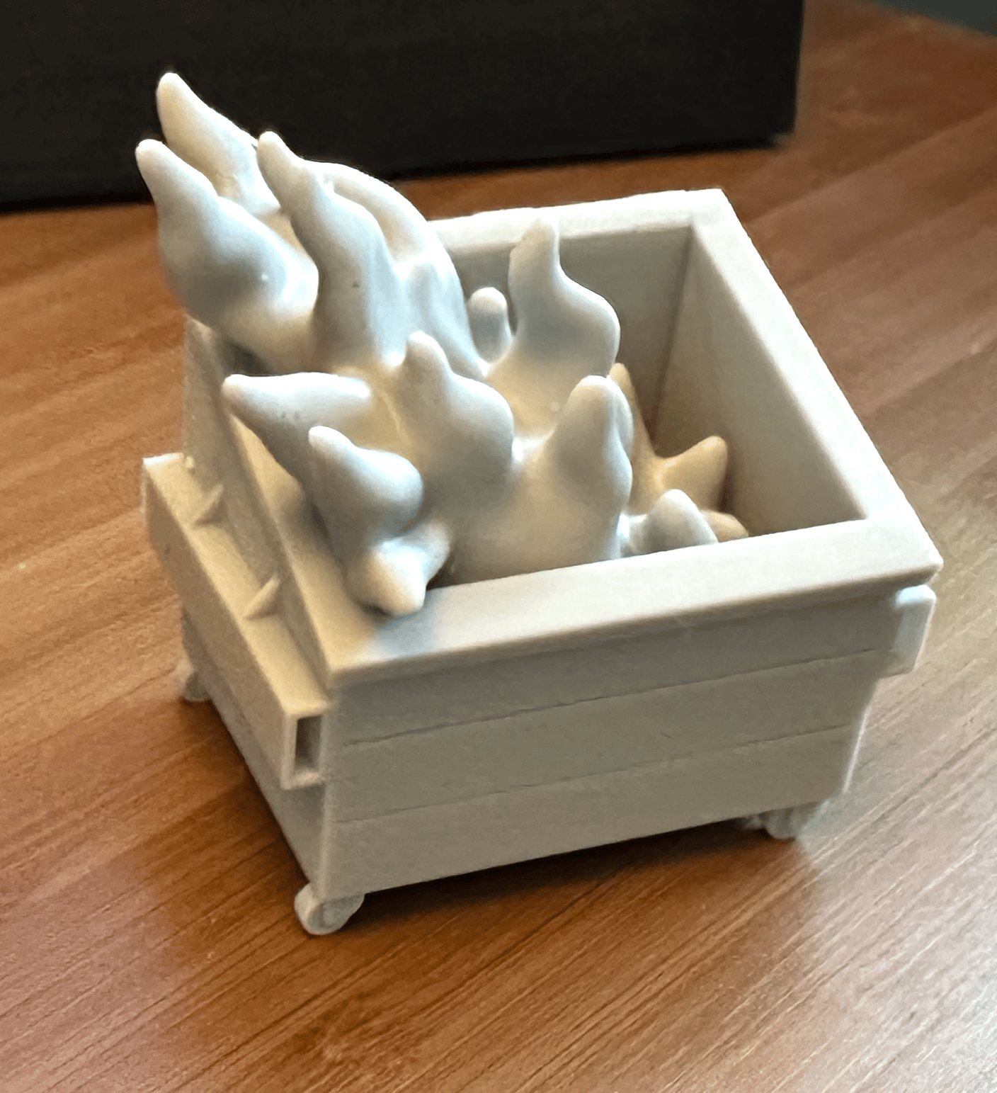 gray 3D print of an open dumpster with massive flames streaming out of it
