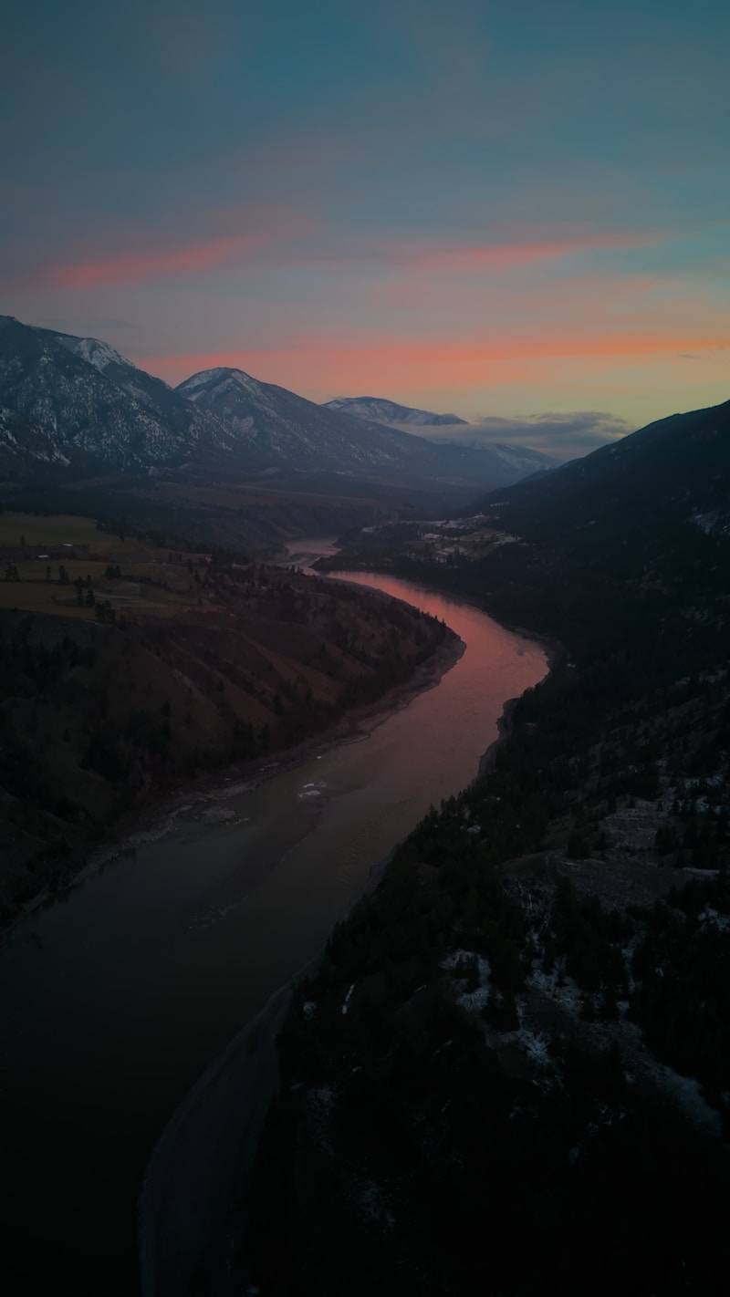 An aerial view of a river and mountains at sunset