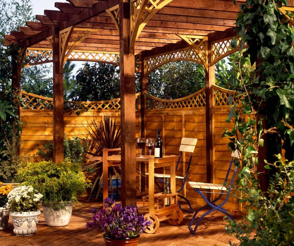 A cozy seating area under a pergola enclosed my lattice edge wooden fencing.