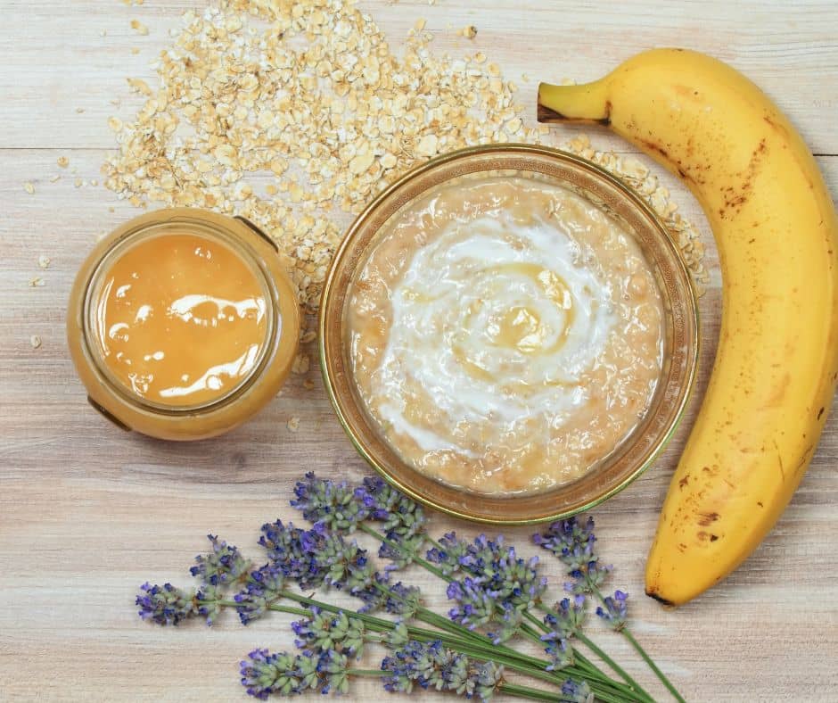 Honey, oats, lavender, and a banana on a wooden table.