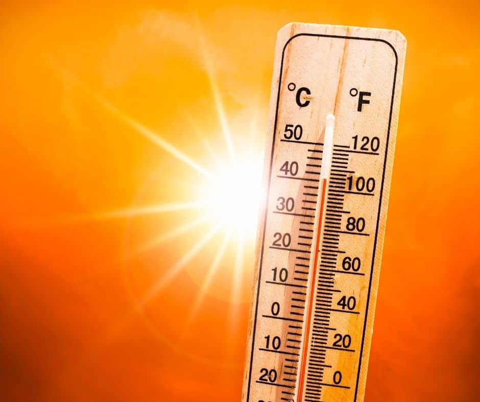 A thermometer reading above 100 degrees Fahrenheit with a bright orange sunset background.