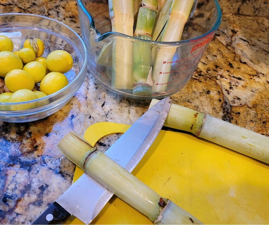 Sugarcane and limes on a countertop being prepped for juicing.
