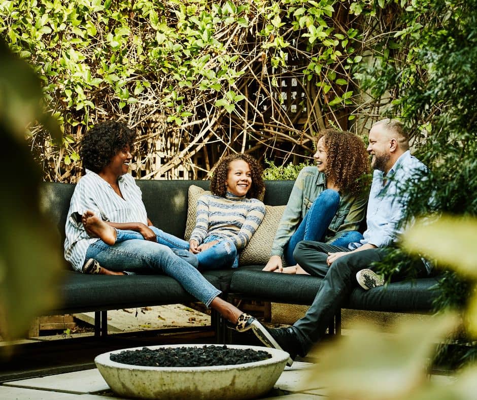 A family relaxing next to a private backyard fire pit.