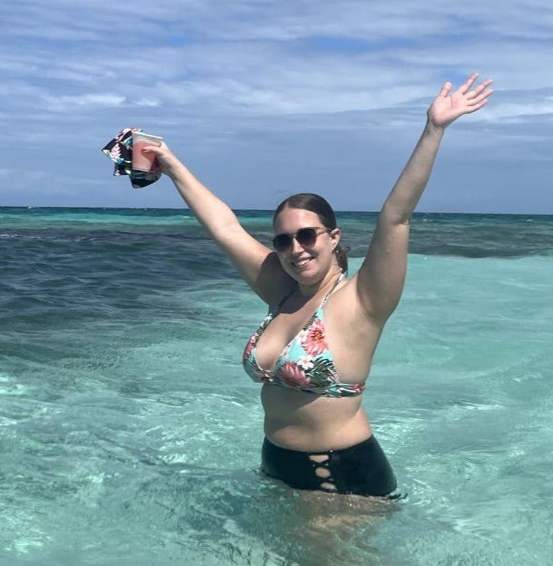 Me raising my hand while holding a drink on the beach.