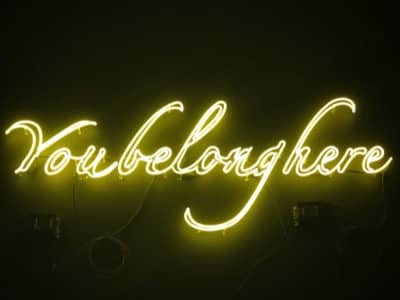 'You belong here" in yellow neon lights