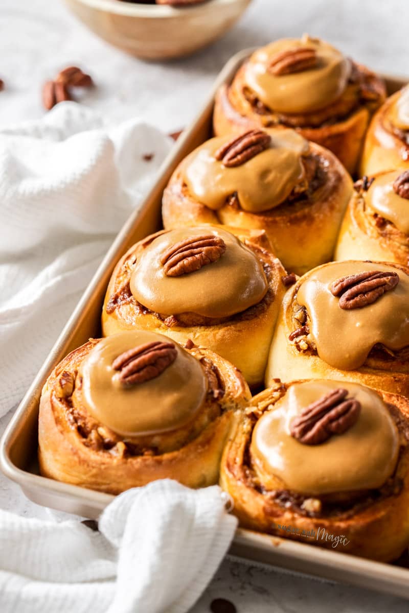 A batch of coffee pecan cinnamon rolls on a baking tray.
