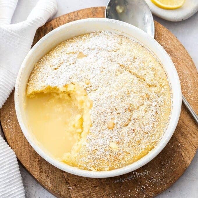 Top down view of a lemon self-saucing pudding on a wooden platter.