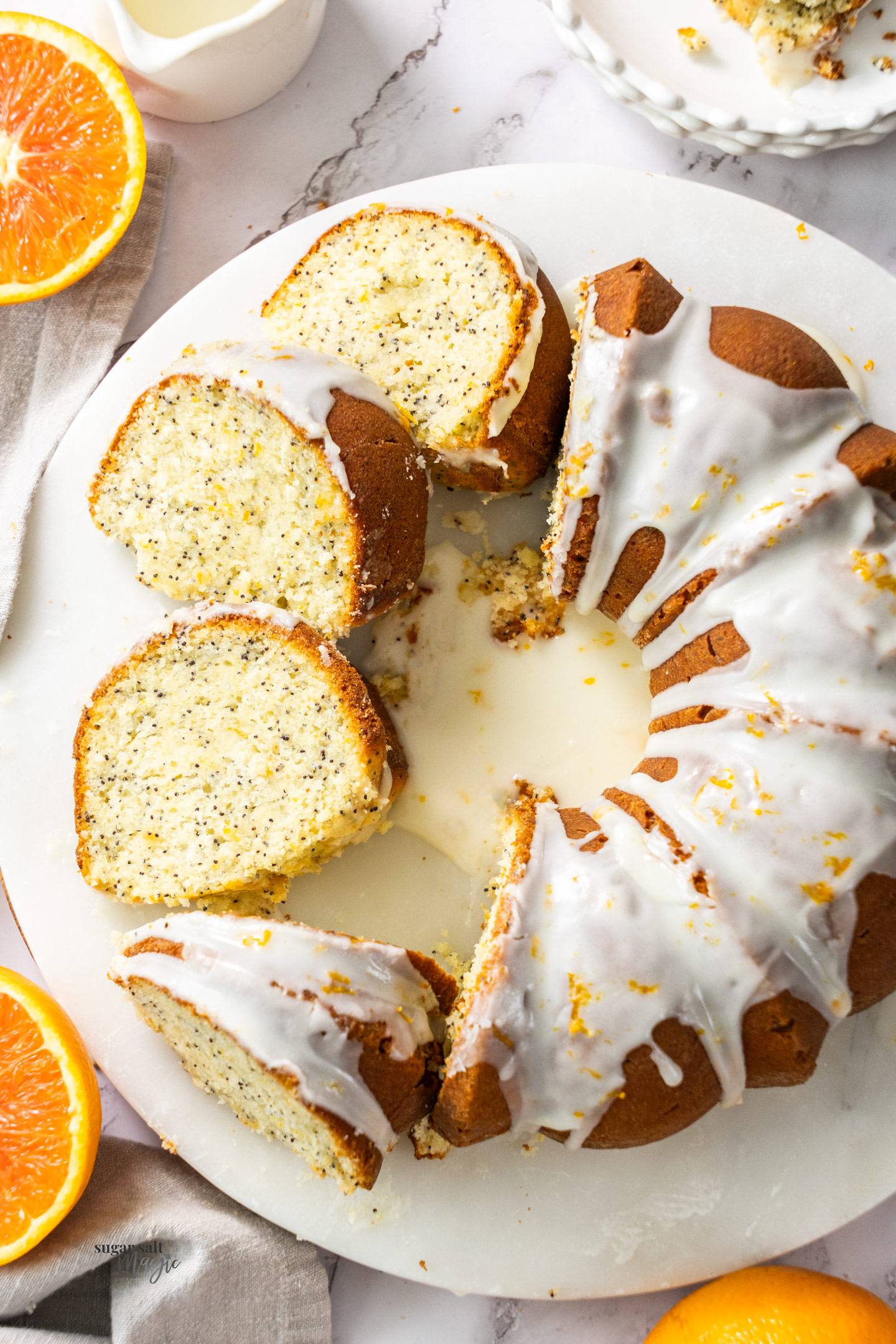 A bundt cake with poppy seeds cut into slices.