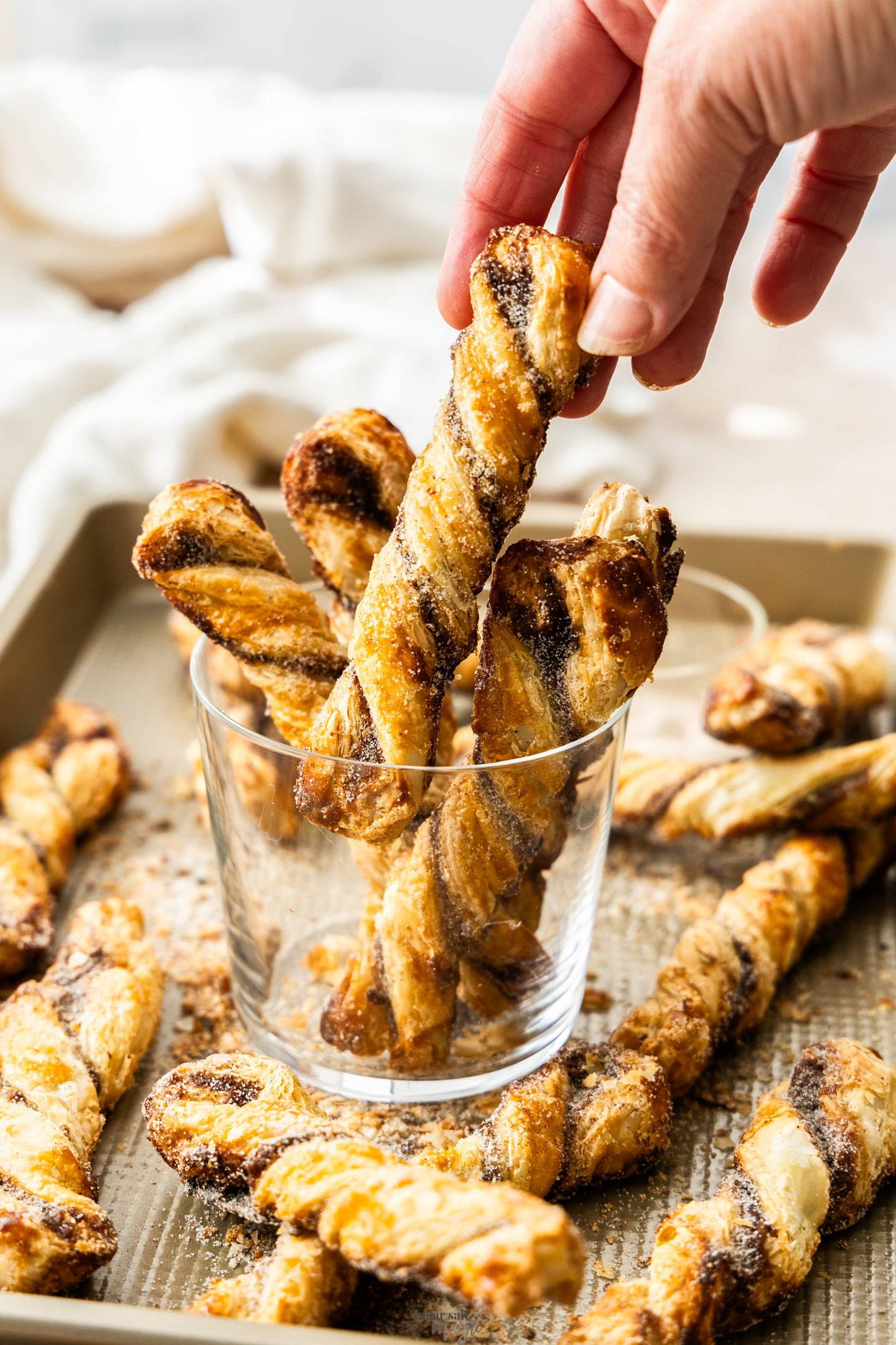 A hand taking a cinnamon twist from a glass.
