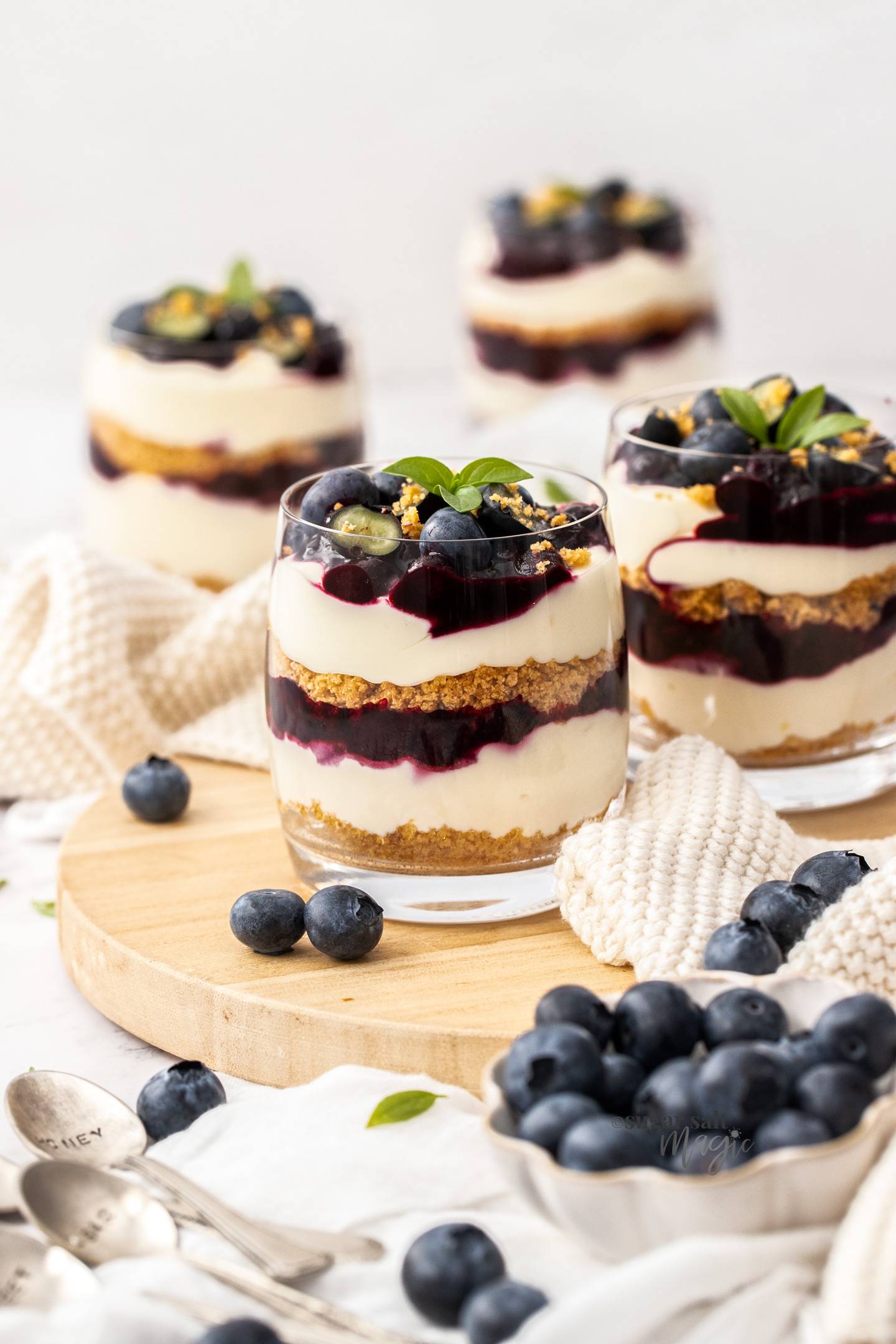 4 glasses filled with layers of blueberry sauce and cream cheese.