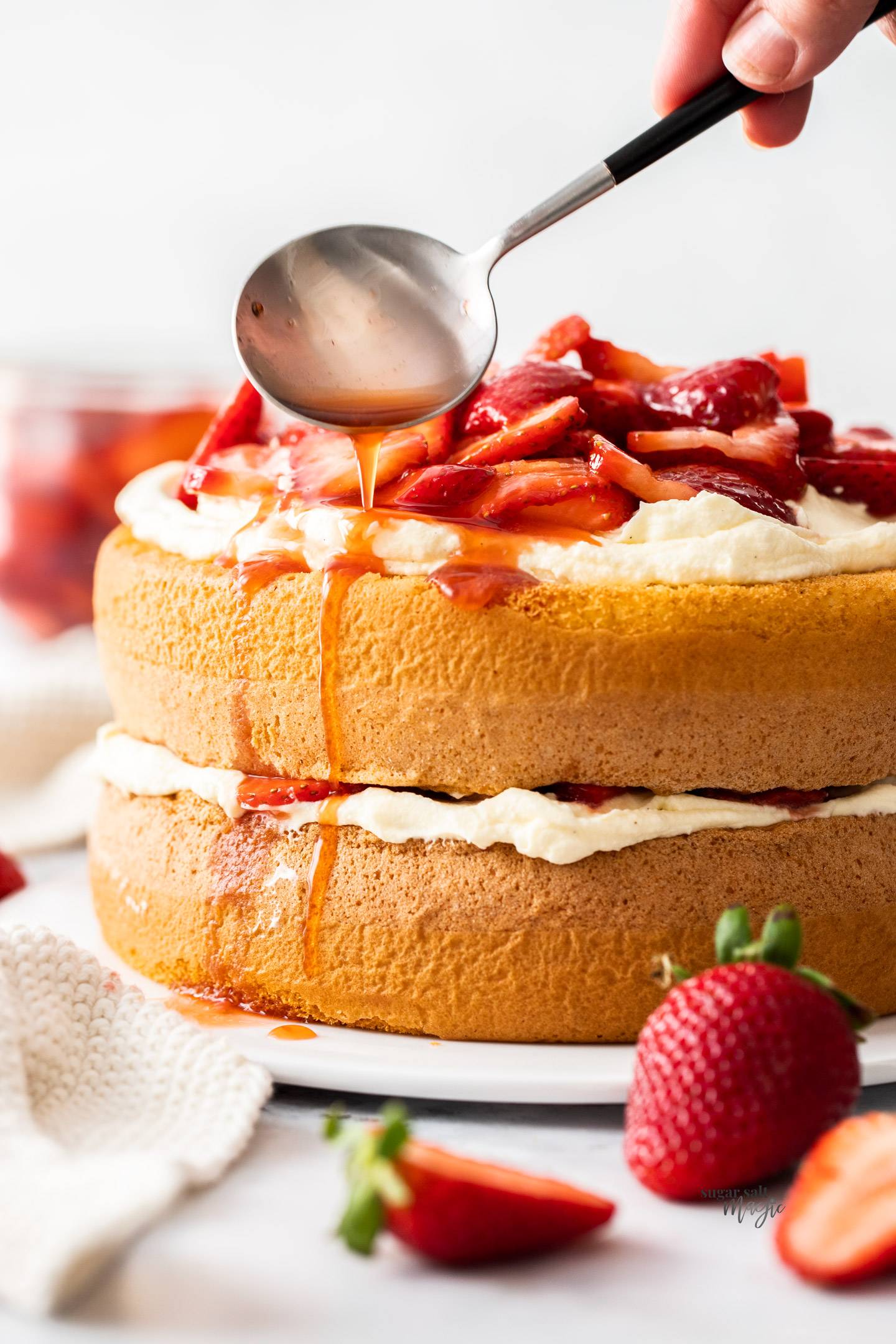 Closeup of a dual layer strawberry sponge cake with cream and strawberries.