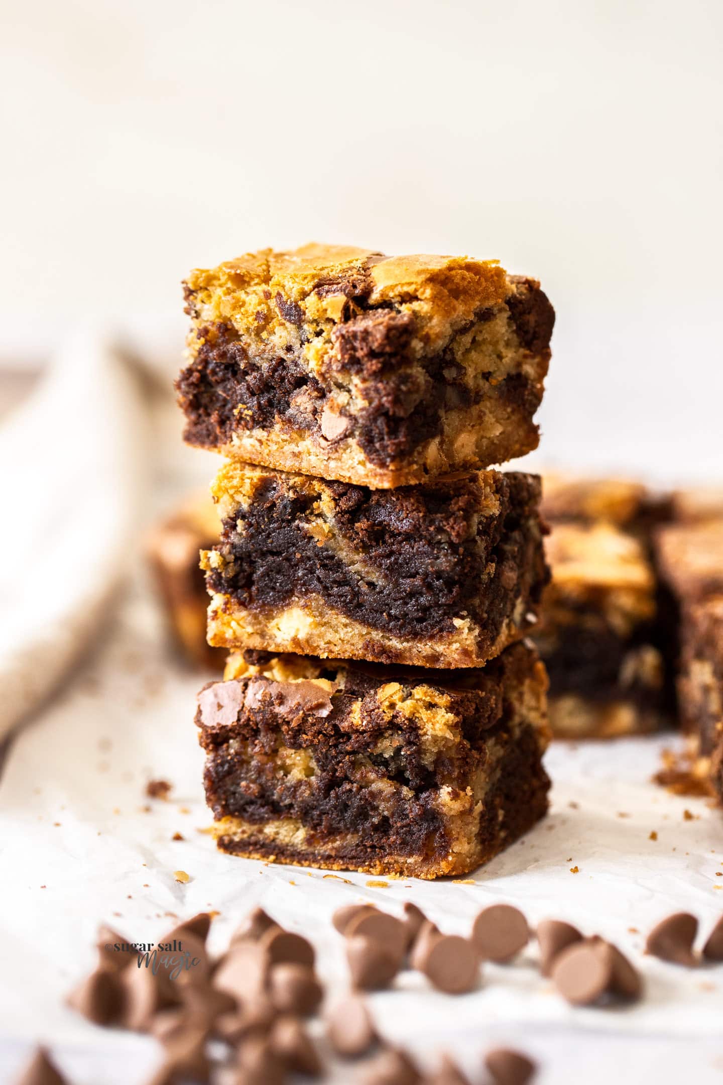 A stack of 3 brownie blondies with chocolate chips scattered around.
