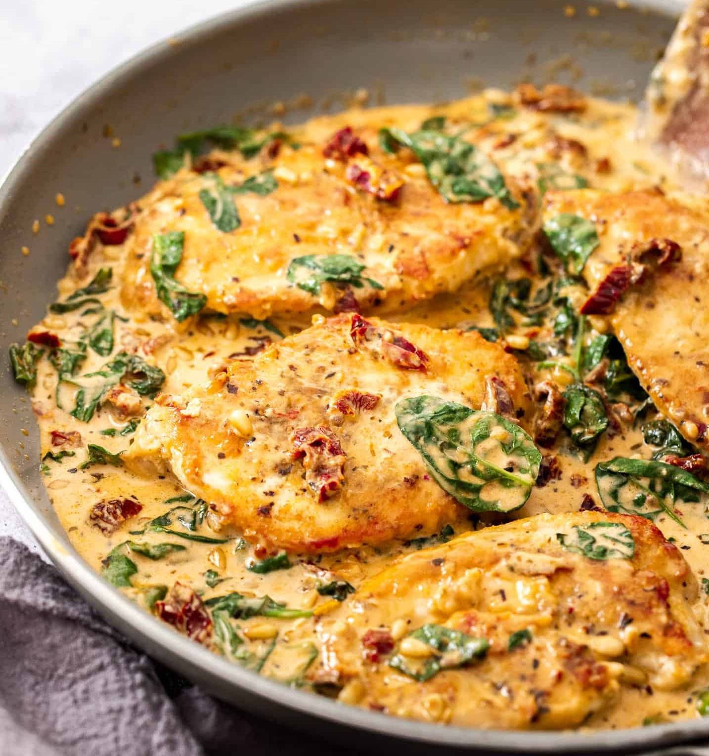 Chicken breasts in a creamy tomato sauce in a pan.