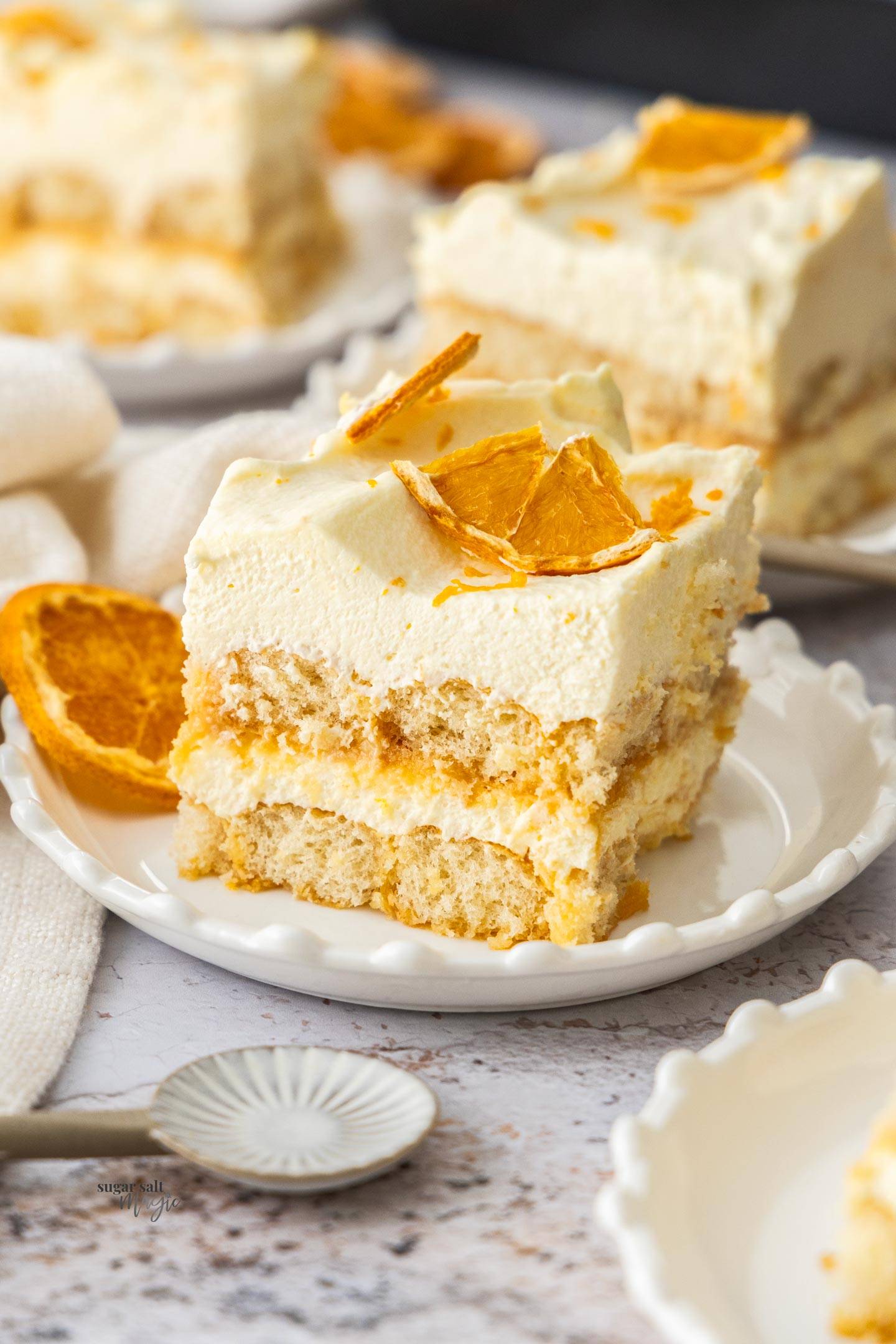 A square slice of orange tiramisu on a dessert plate.