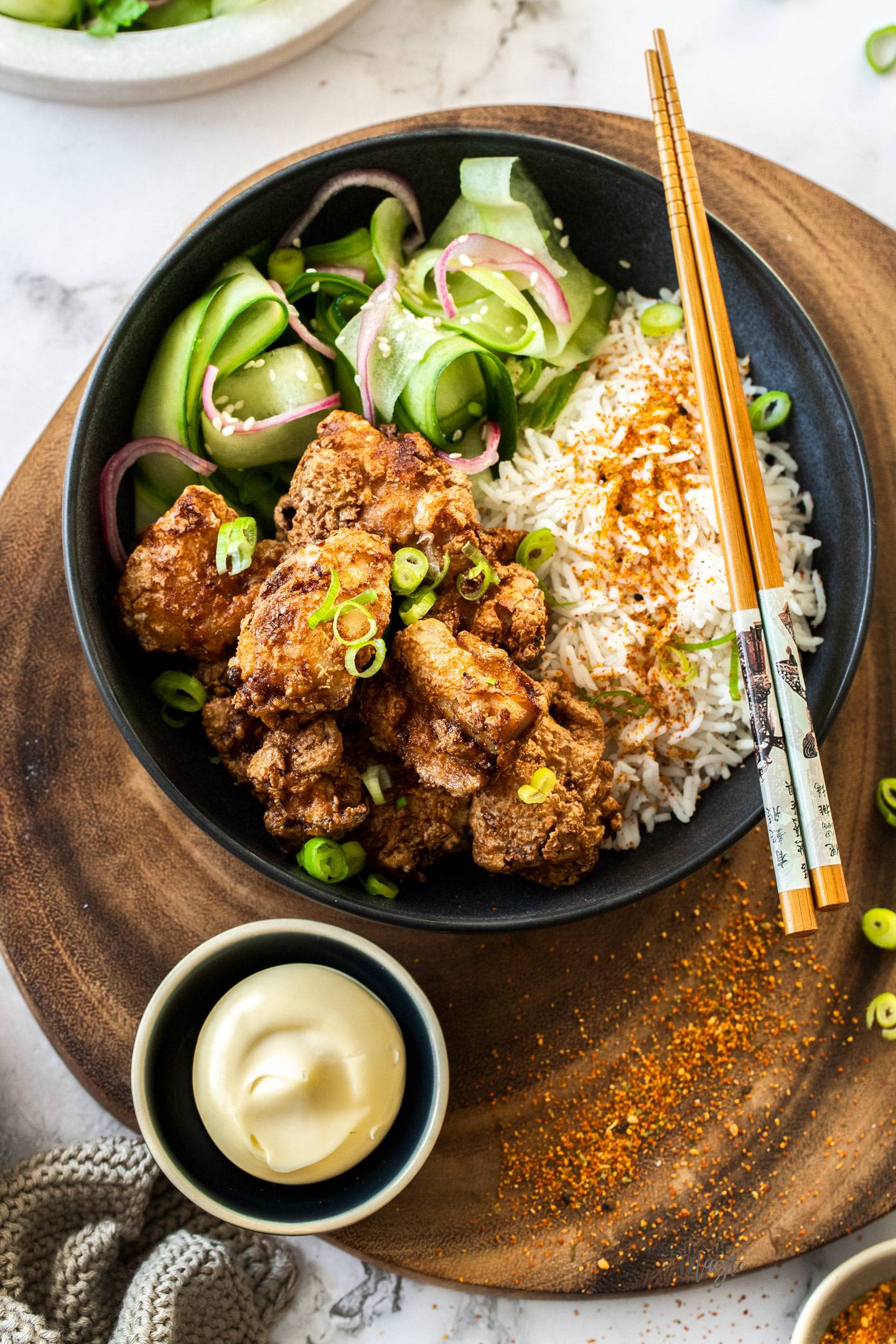 Top down view of karaage chicken with rice and cucumber.
